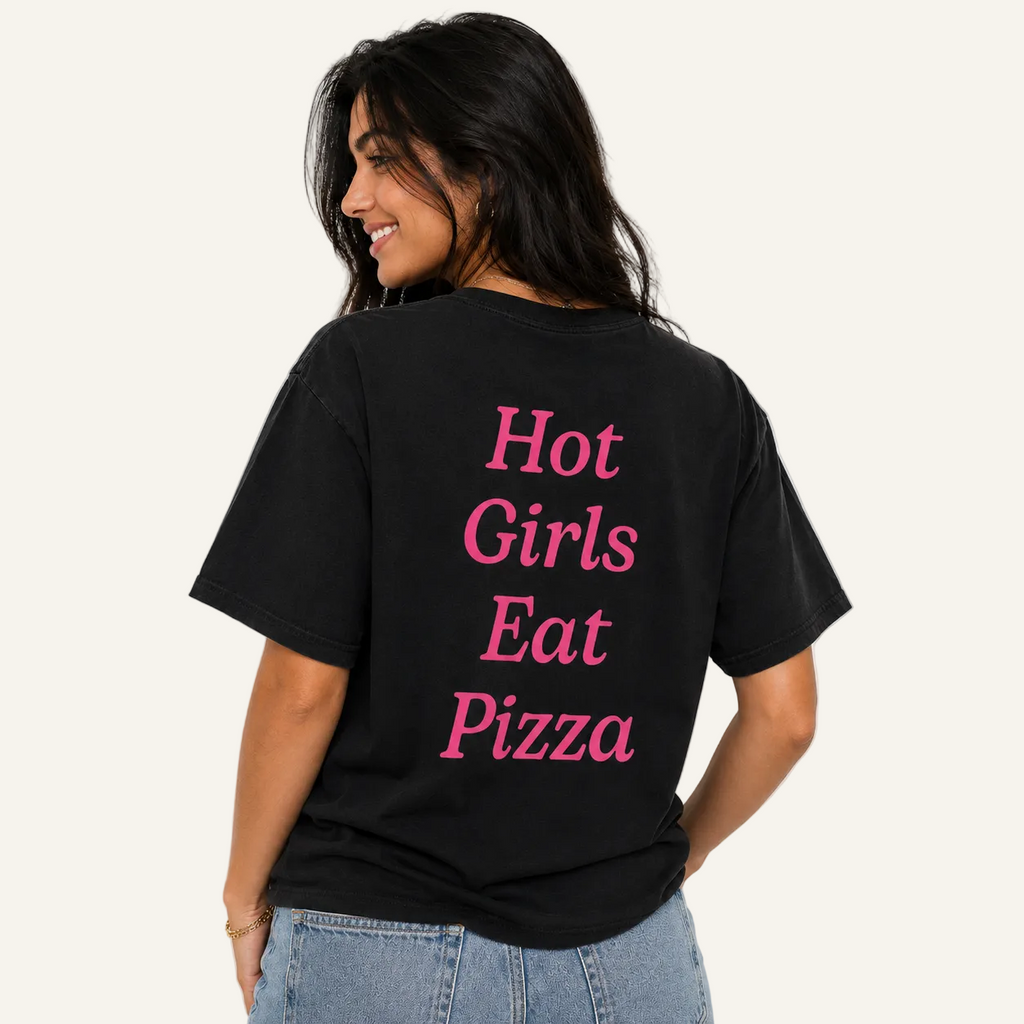 A woman wearing a black t-shirt with the phrase 'Hot Girls Eat Pizza' printed in pink text on the back, shown from behind against a plain white background.