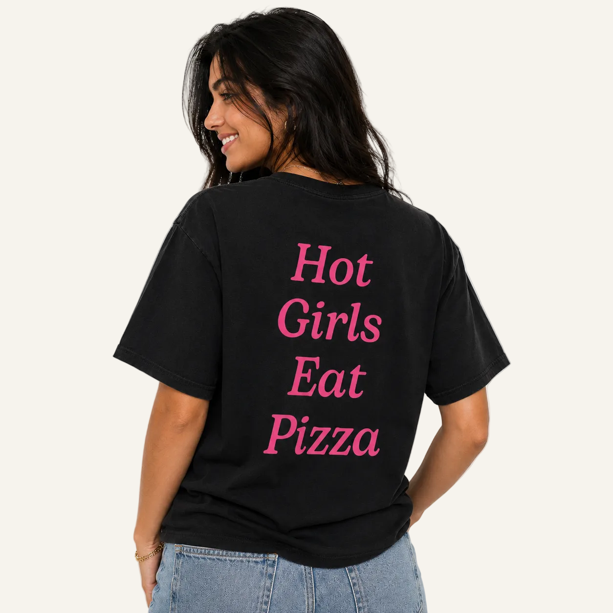 A woman wearing a black t-shirt with the phrase 'Hot Girls Eat Pizza' printed in pink text on the back, shown from behind against a plain white background.