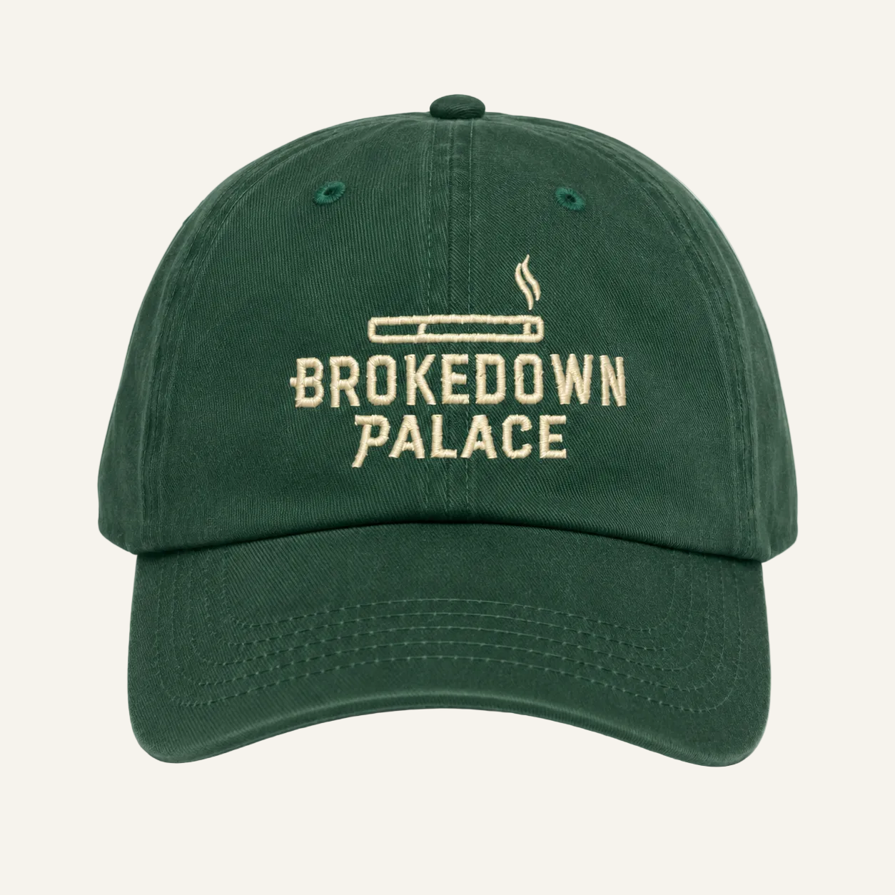 A dark green baseball cap with 'BROKEDOWN PALACE' embroidered in beige on the front, featuring a cigarette graphic above the text.
