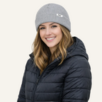 Woman wearing a gray beanie and black puffer jacket on a white background
