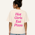 A woman shown from the back wearing a cream-colored oversized t-shirt with the phrase 'Hot Girls Eat Pizza' printed in bright pink text on the back.
