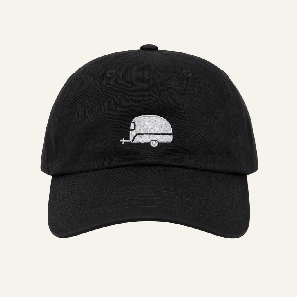 A black dad hat baseball cap featuring a small white embroidered retro camper graphic on the front, set against a plain white background.
