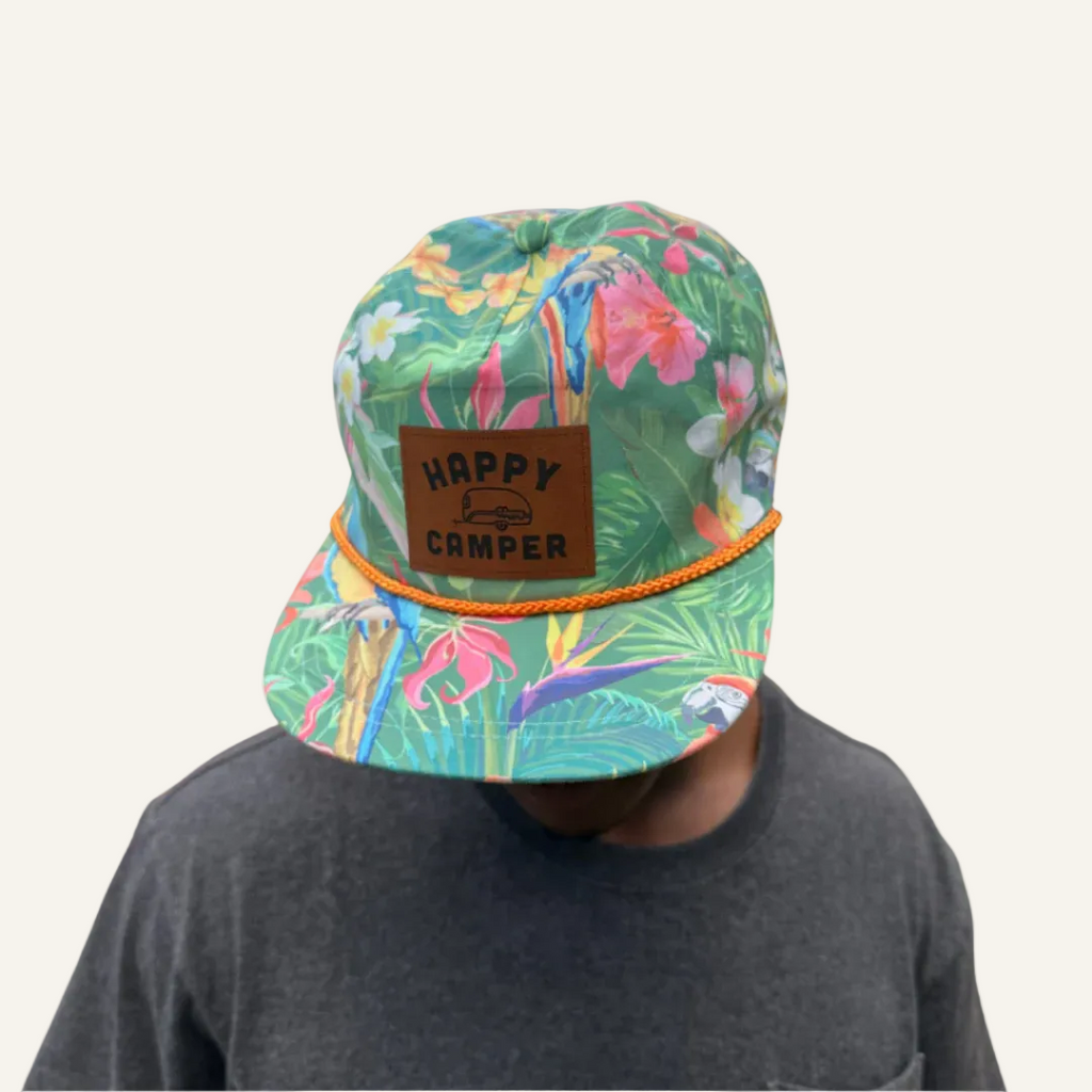 Colorful cap with tropical pattern and 'Happy Camper' label on a white background